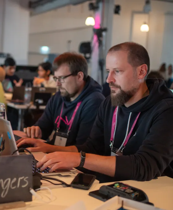 Two developers collaborate at the Eclipse Software Defined Vehicle Hackathon, focused on coding on their laptops during the event.
